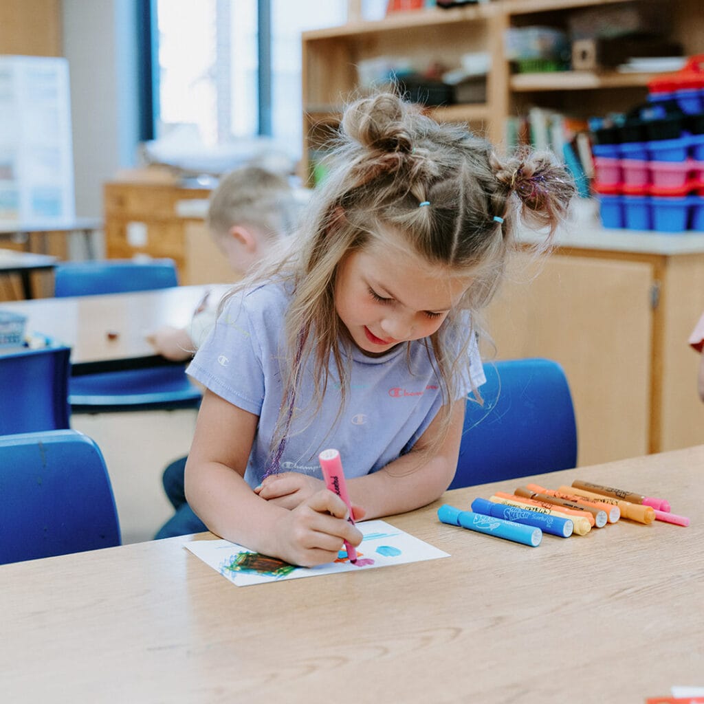 Girl coloring with markers at desk