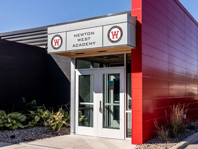 Exterior of WEST Academy, a building that is modern, with grey and red exterior coloring.